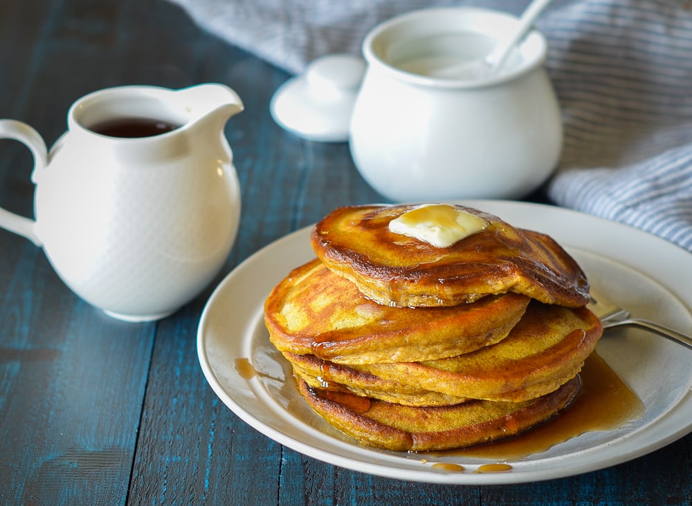 pumpkin pancakes on a plate with maple syrup and butter