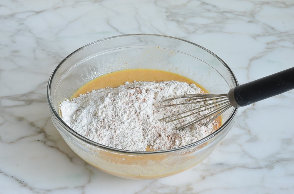 adding dry ingredients to wet ingredients for pumpkin pancakes