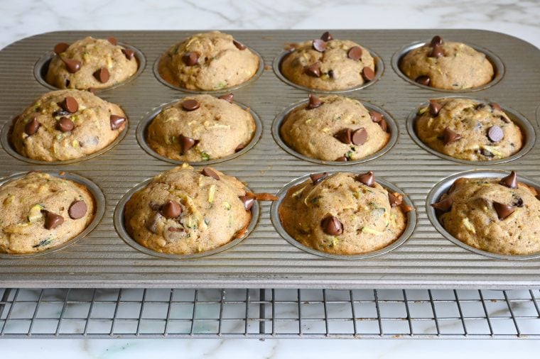 baked zucchini muffins sitting in pan on rack