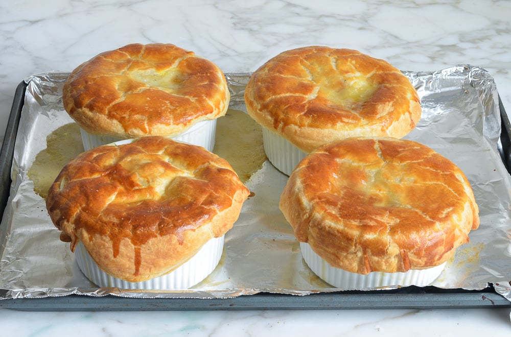Four pot pies on a lined baking sheet.