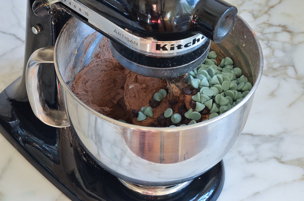 Chocolate and mint chips in a stand mixer with chocolate dough.