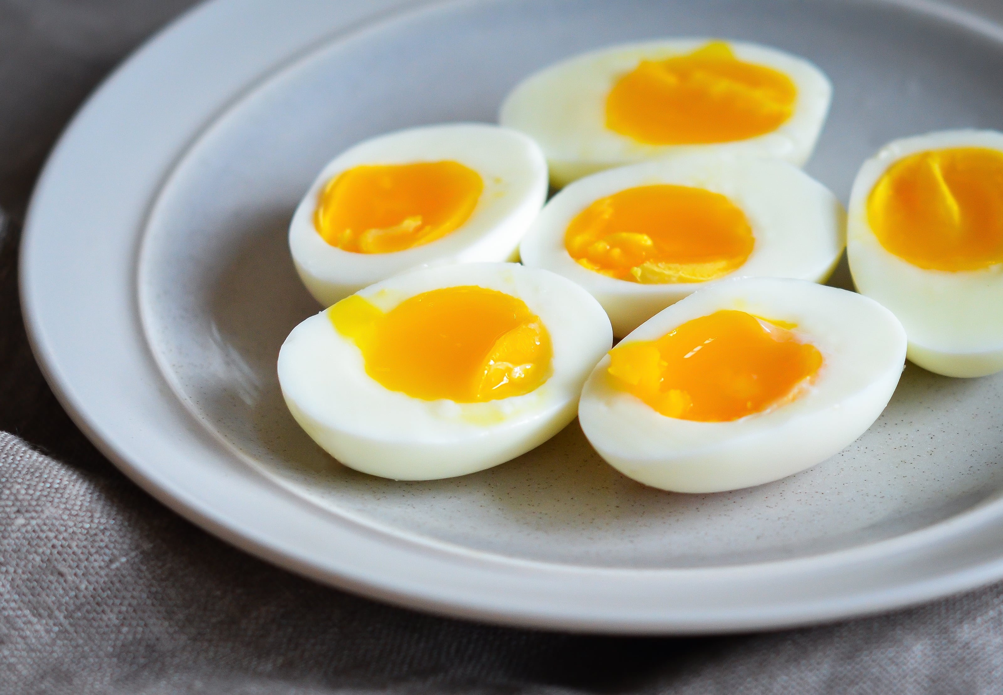 Perfect soft-boiled eggs cut in half on a plate.
