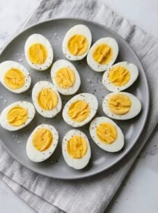 Halved hard-boiled eggs arranged on gray platter.