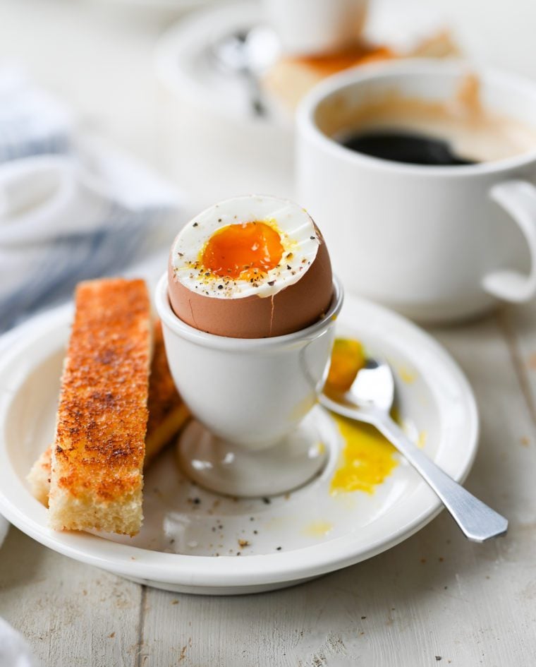 Soft-boiled egg with the top removed in an egg cup.