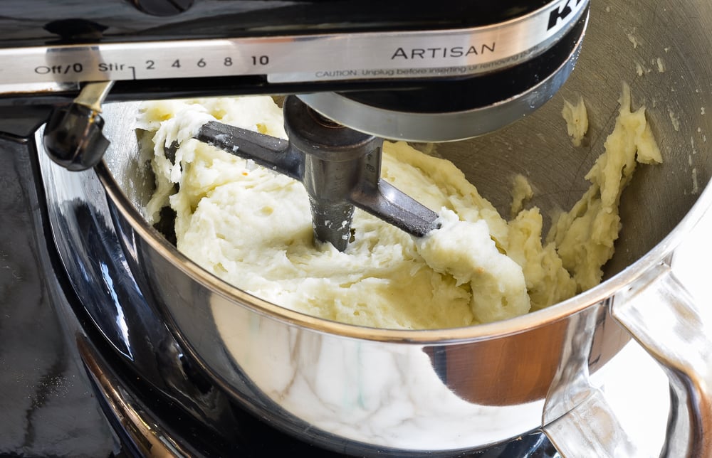 Stand mixer full of processed potatoes.