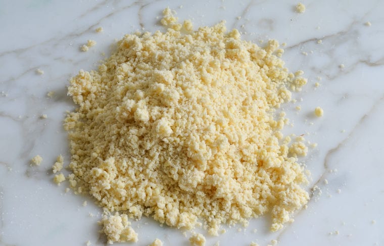 Pile of crumbly pie crust dough on a marbled surface.