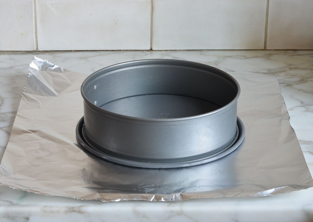 Springform pan on a sheet of aluminum foil.