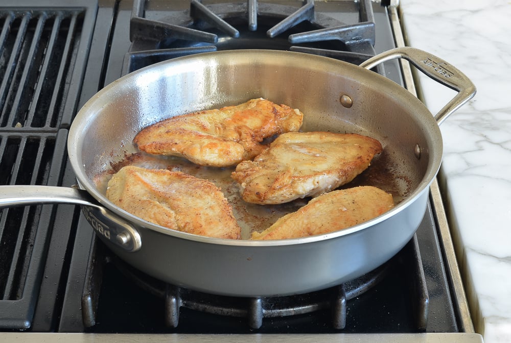 Partially-cooked chicken in a skillet.