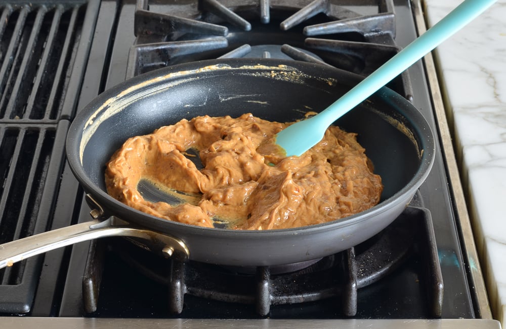 Spatula stirring a peanut butter mixture in a skillet.