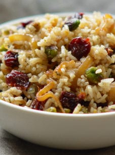 Bowl of rice pilaf with caramelized onion, orange, cherry, and pistachio.