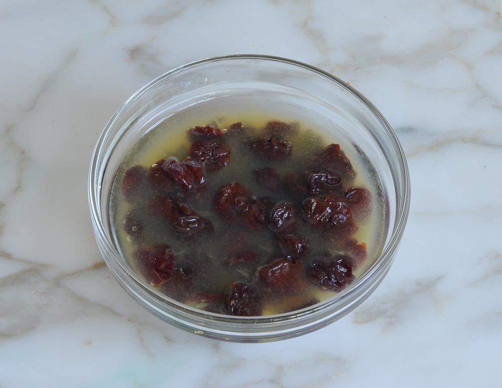 Cherries in a bowl of orange juice.