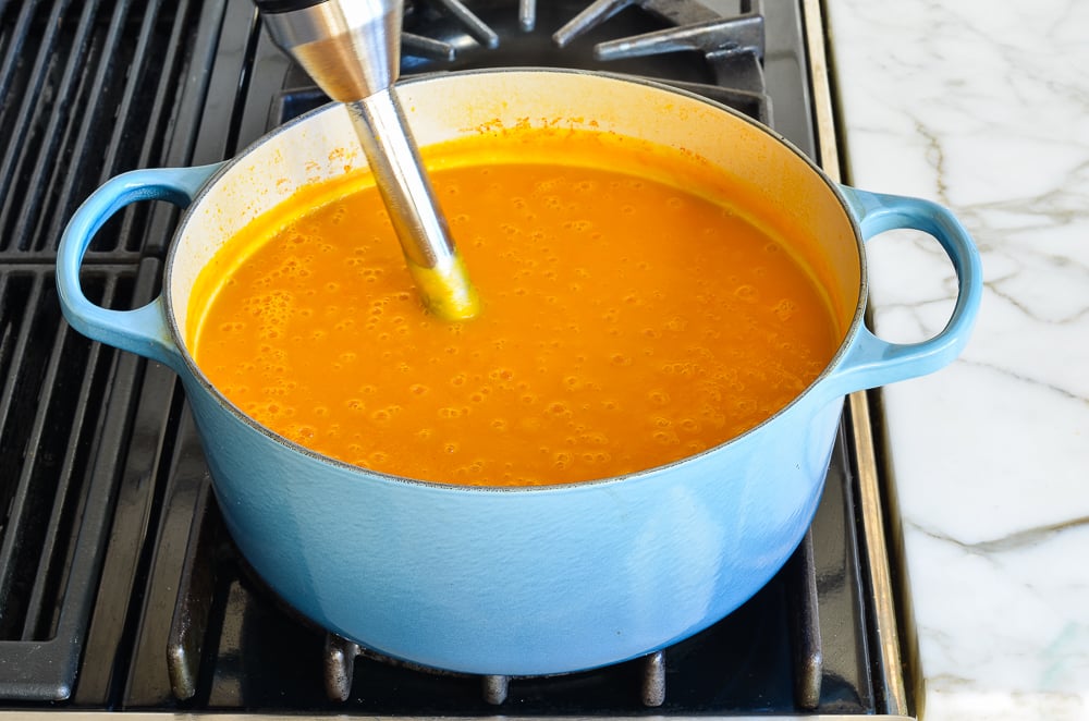 Immersion blender in a Dutch oven of soup.