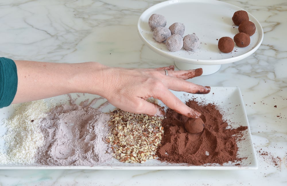 Person rolling a truffle in cocoa powder.