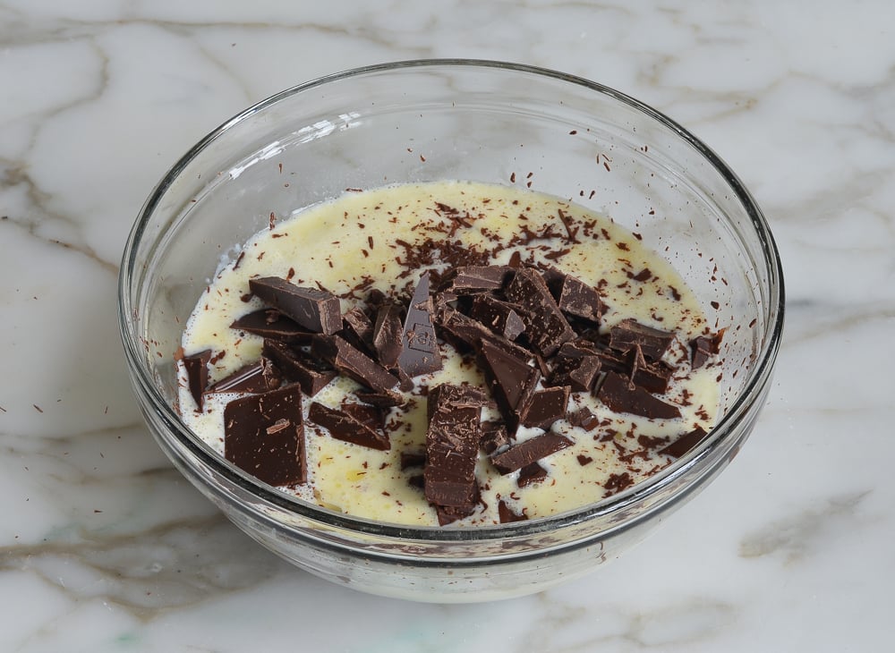 Chocolate melting into a bowl of Baileys mixture.