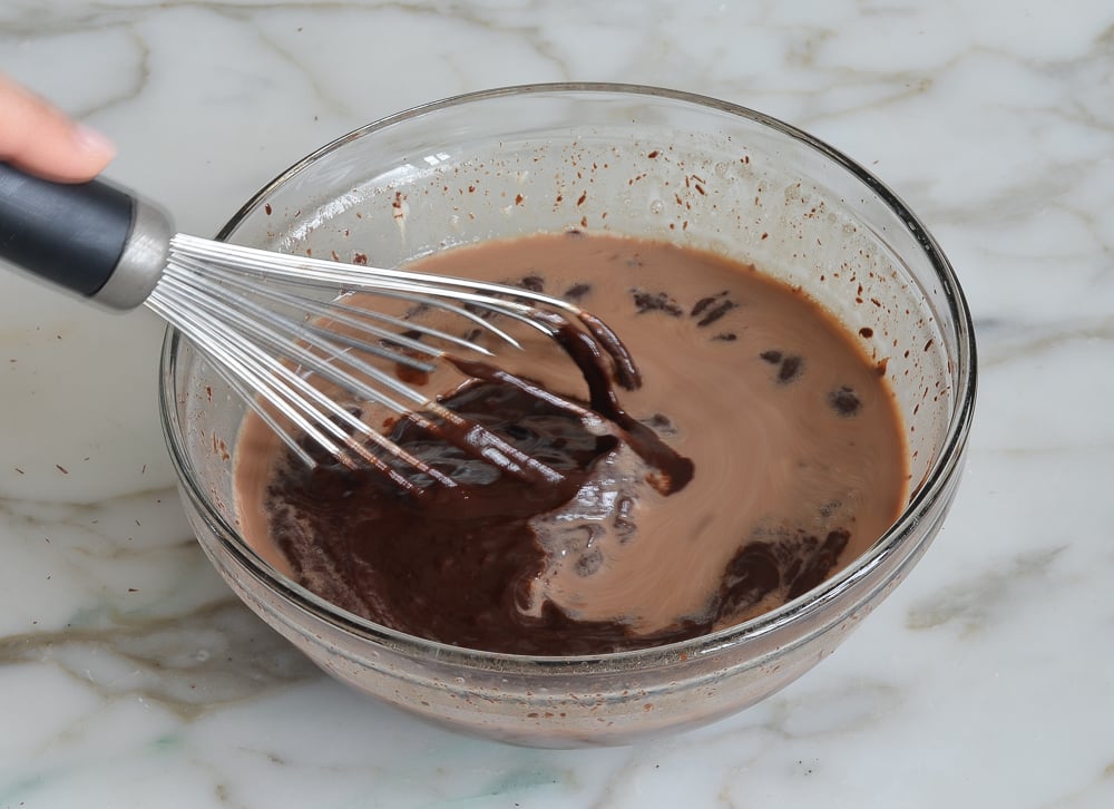 Whisk stirring melted chocolate into a Baileys mixture.