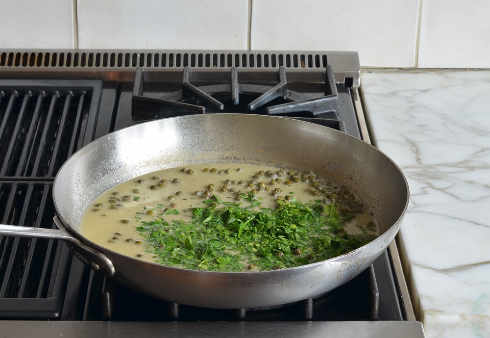 finishing chicken piccata sauce with parsley.