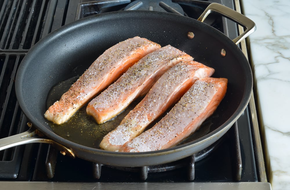 Seasoned salmon in a skillet.