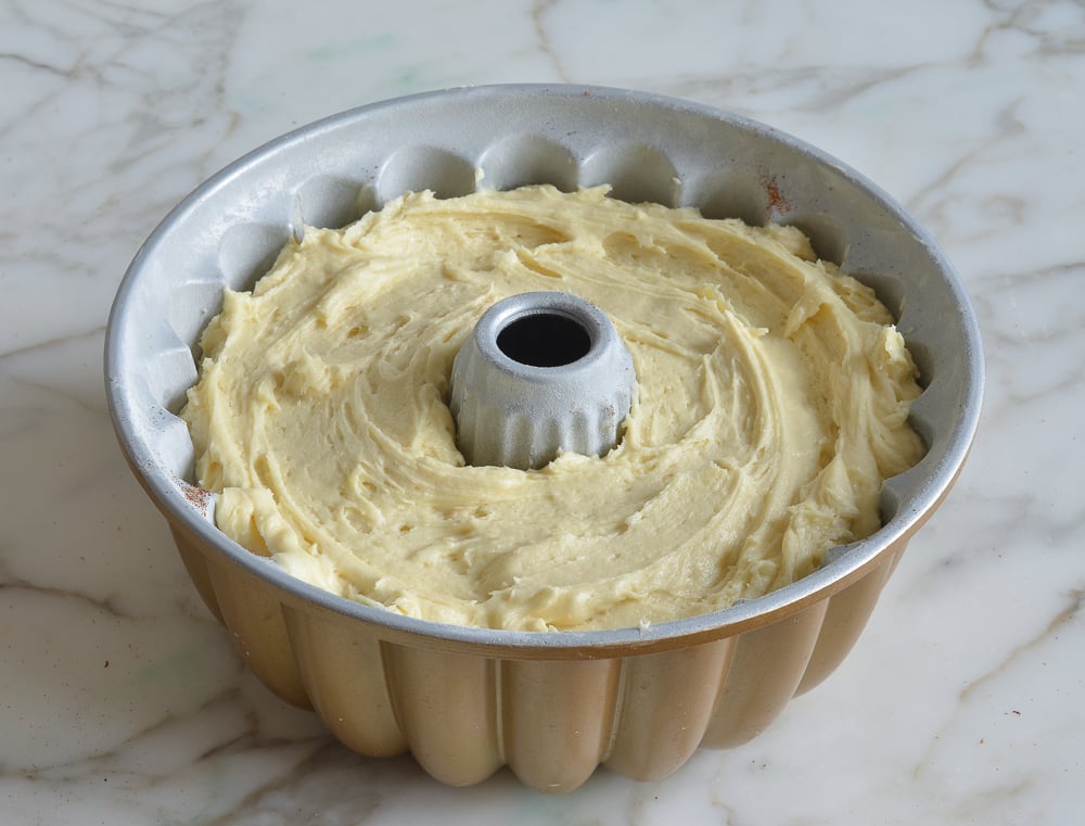 Layer of sour cream coffee cake batter to the top of a Bundt pan.