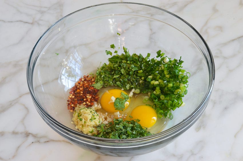 Eggs, seasonings, and minced vegetables in a bowl.
