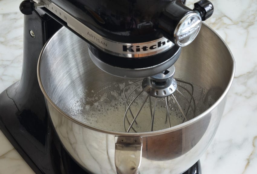 Bowl in a stand mixer with a whisk attachment.