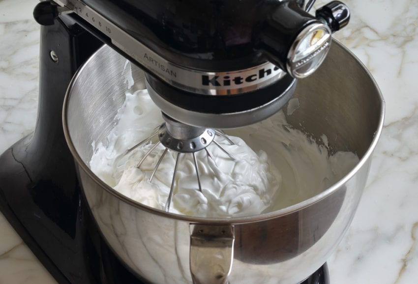 Thick, glossy egg white mixture in a stand mixer.
