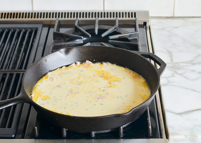 Egg mixture in a skillet with ham.