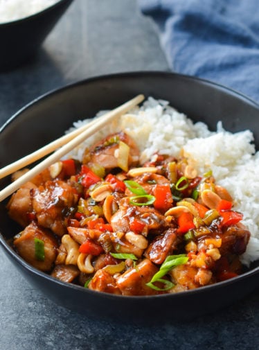 Chopsticks on a bowl of Kung Pao chicken with rice.