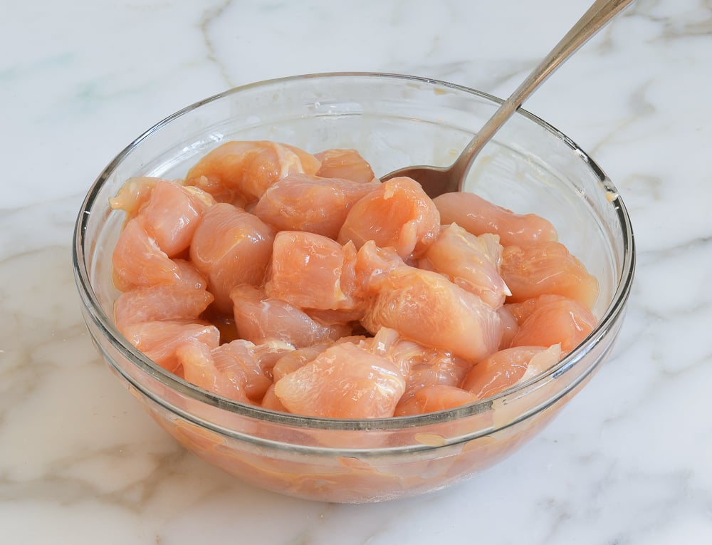 marinating chicken pieces in glass bowl.