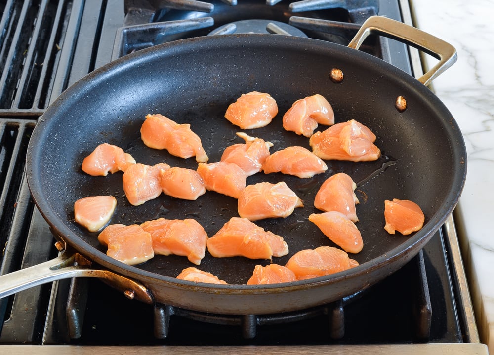 searing chicken pieces in skillet.
