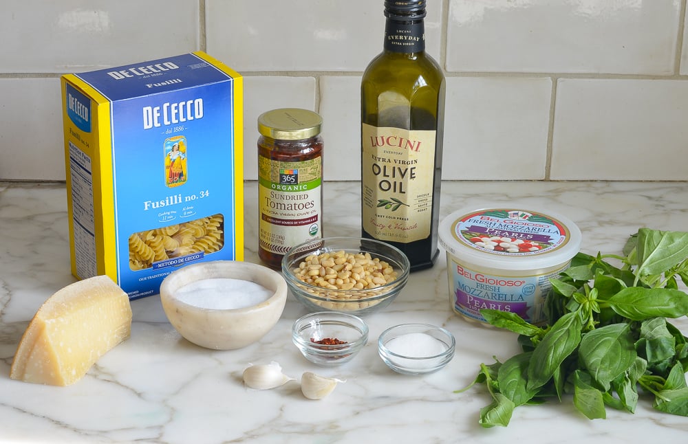 Pasta ingredients including olive oil, mozzarella pearls, and sun-dried tomatoes.