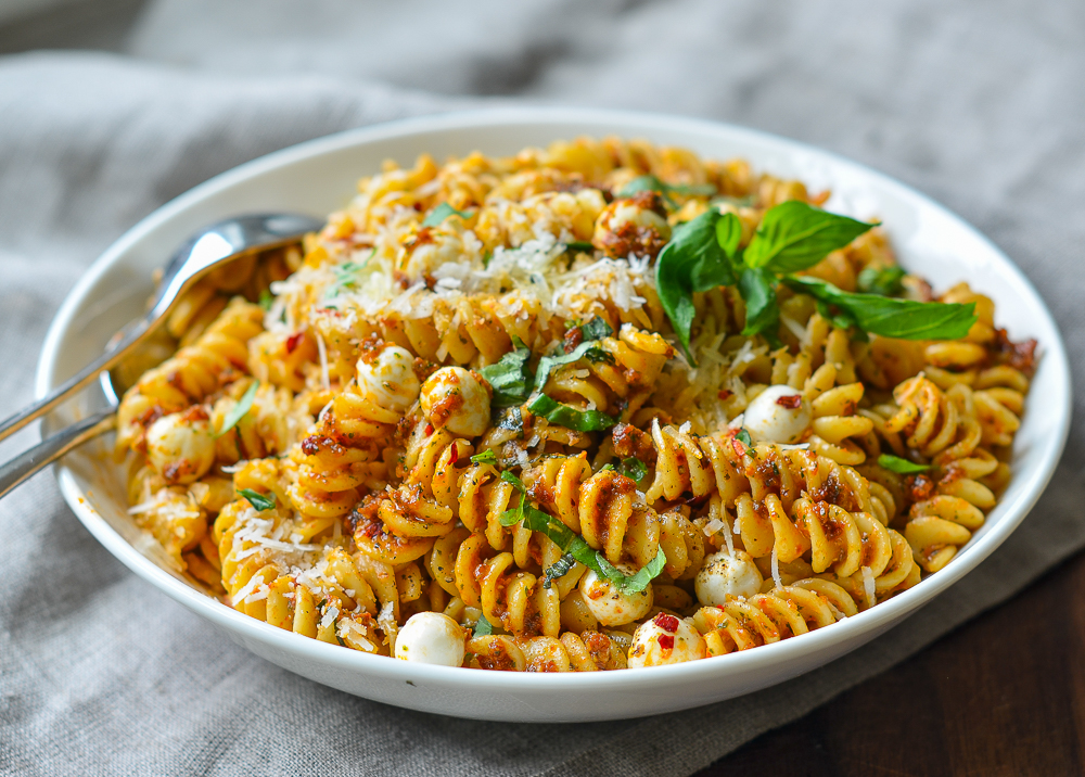 Bowl of pasta with sun-dried tomato pesto and mozzarella pearls.