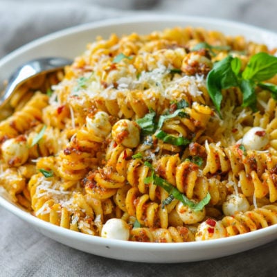 Bowl of pasta with sun-dried tomato pesto and mozzarella pearls.