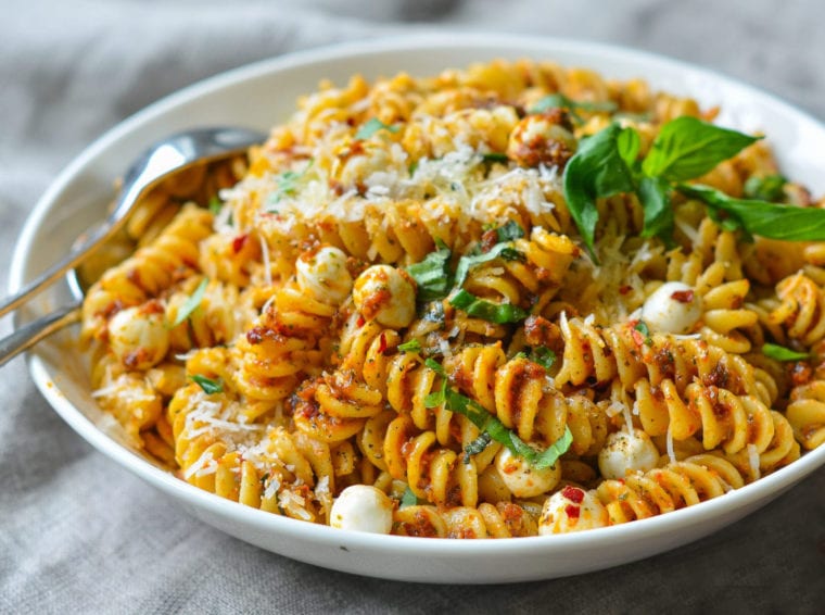 Bowl of pasta with sun-dried tomato pesto and mozzarella pearls.