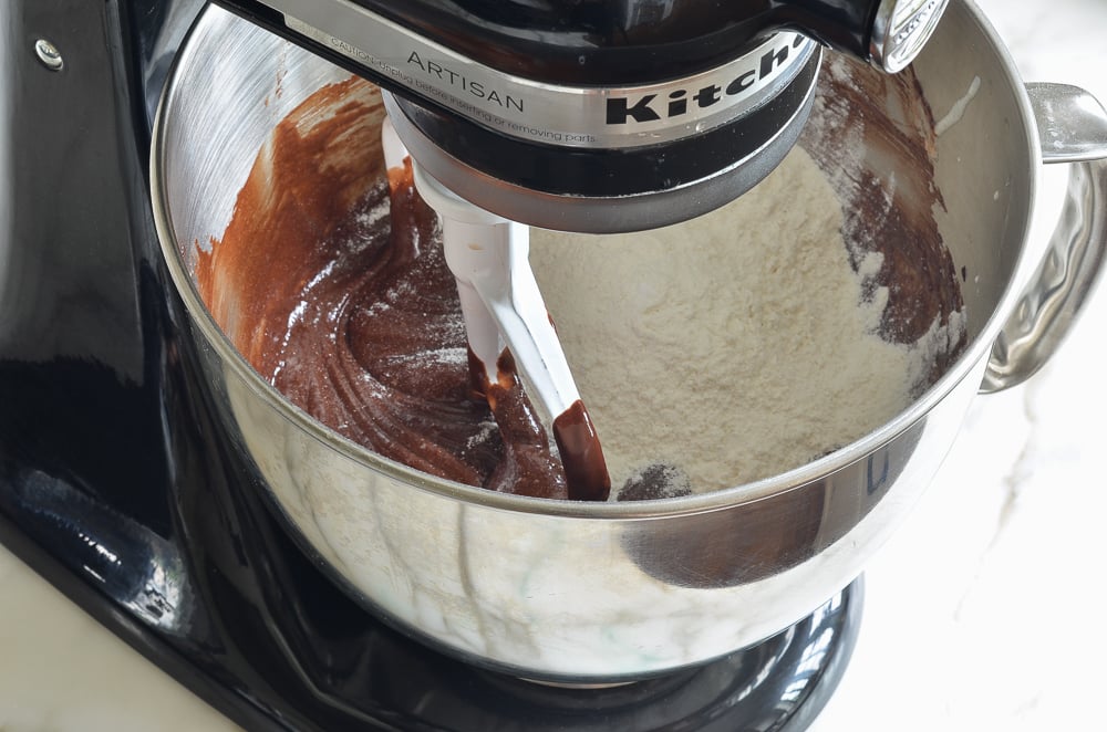 Flour in a stand mixer with a chocolate batter.