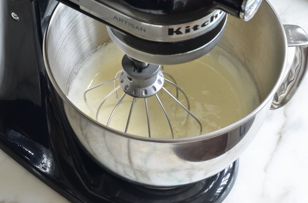 Creamy egg and sugar mixture in a stand mixer.