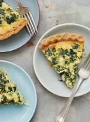 Slices of Spinach Quiche on plates with forks.