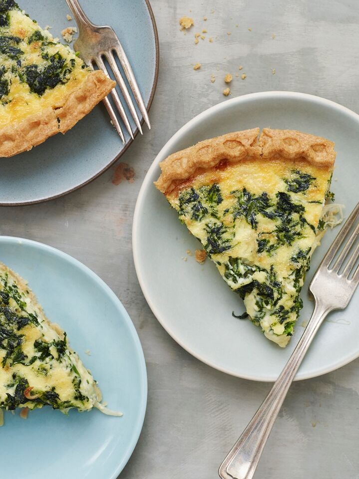 Slices of Spinach Quiche on plates with forks.