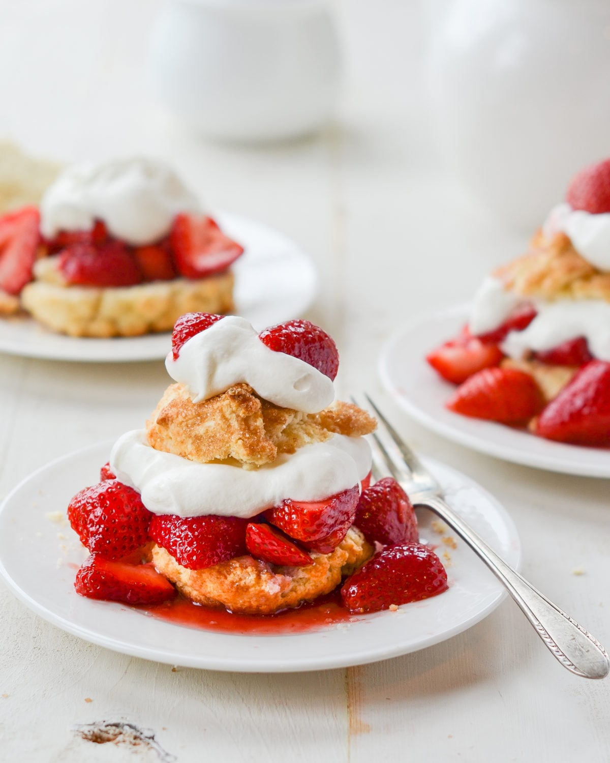 Plates of Strawberry Shortcake on a table with a fork on one.