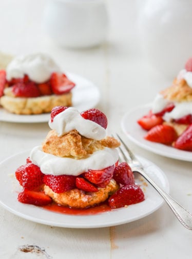 Plates of Strawberry Shortcake on a table with a fork on one.