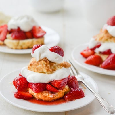 Plates of Strawberry Shortcake on a table with a fork on one.