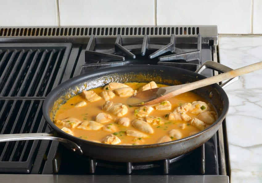 Cooked chicken in a skillet with a coconut milk mixture.