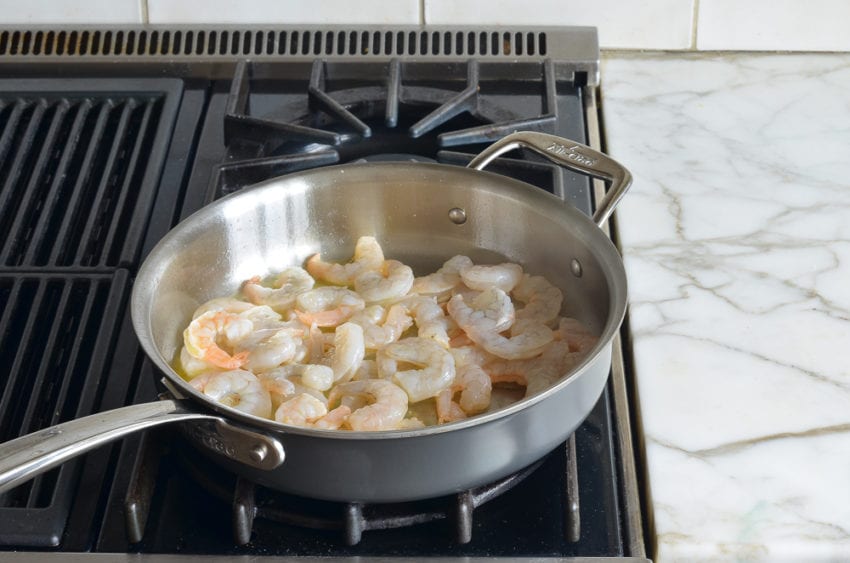 Shrimp cooking in oil on a stovetop.