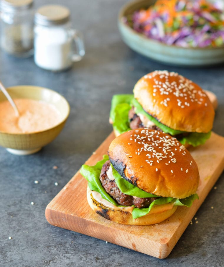 Two bulgogi burgers on a wooden board.
