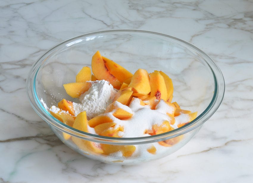 Bowl of unmixed peach filling ingredients.