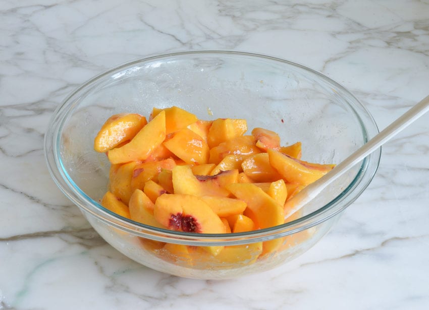 Bowl of peaches mixed with a sugar mixture.
