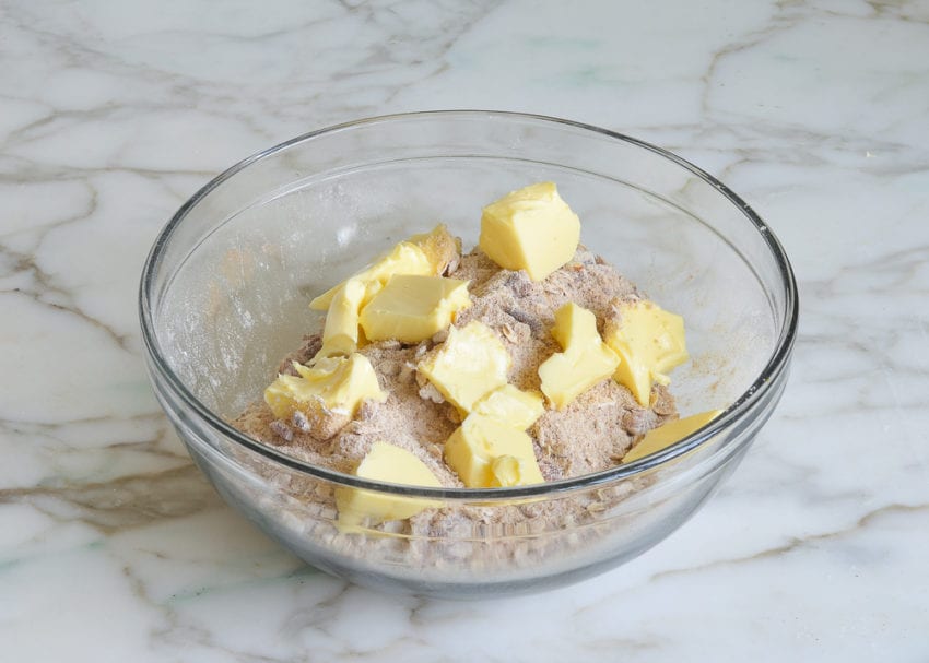 Butter in a bowl with a nut and oat mixture.