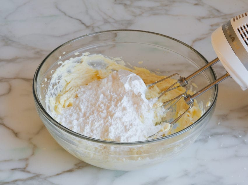 Confectioner's sugar in a bowl with a cream cheese mixture.