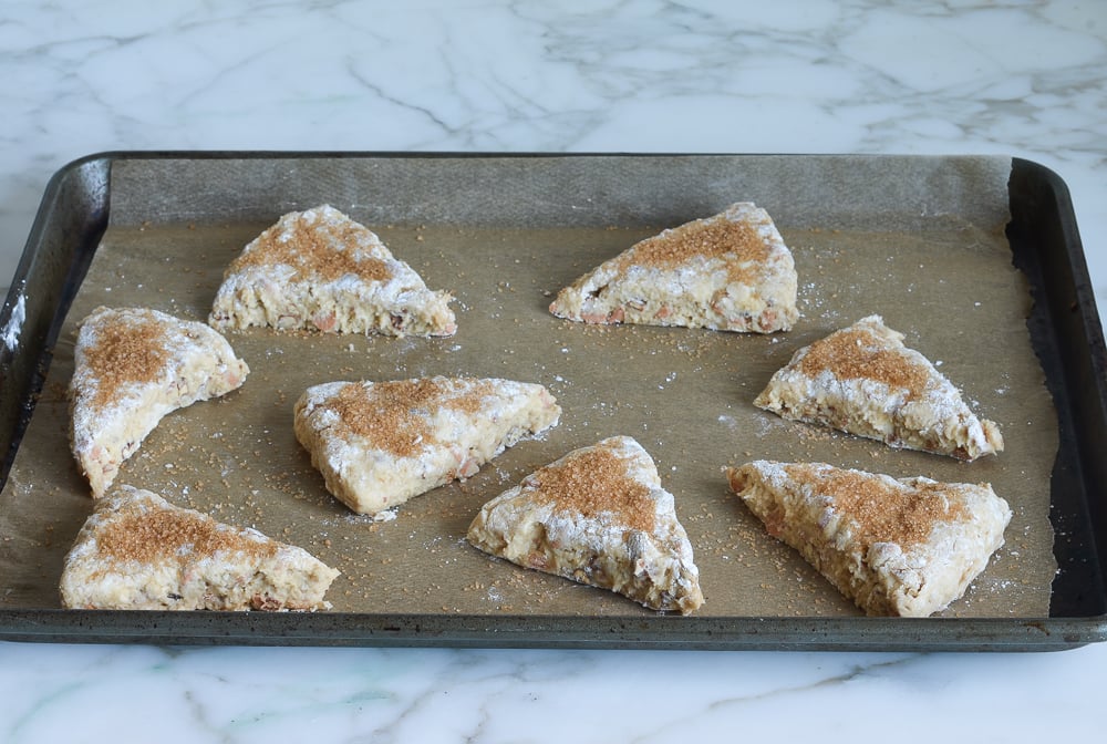 Wedges of dough topped with demerara sugar on a lined baking sheet.