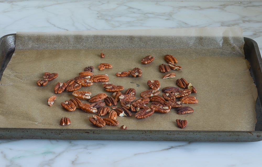 Pecans on a lined baking sheet.