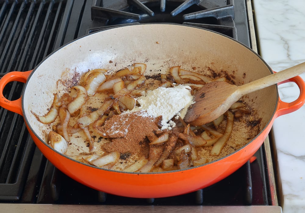 Spices and flour in a skillet with browned onions.